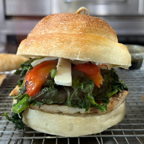 Angelo's Pizzeria and Ristorante's sandwich with greens, red peppers, and cheese on a bun.