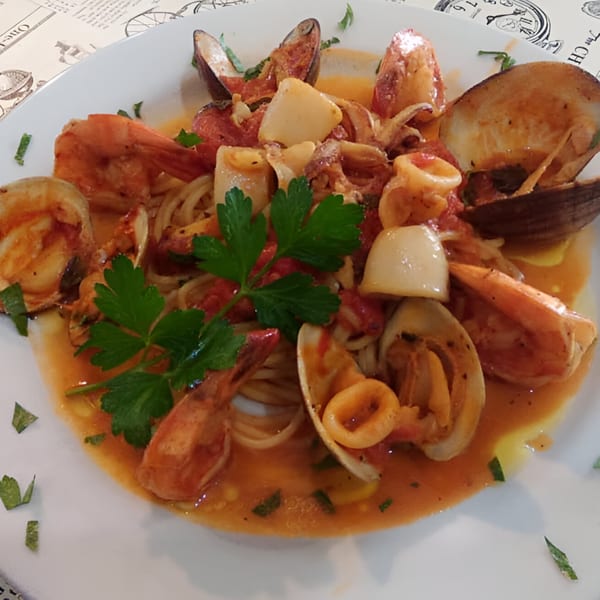 A plate of Angelo's Pizzeria and Ristorante's seafood pasta with shrimp, clams, and calamari.