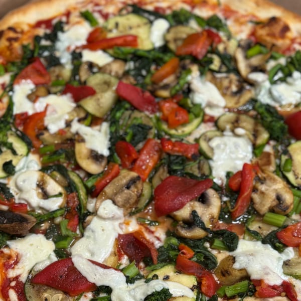 Close-up of Angelo's Pizzeria's vegetable pizza with red peppers, zucchini, mushrooms, and ricotta.