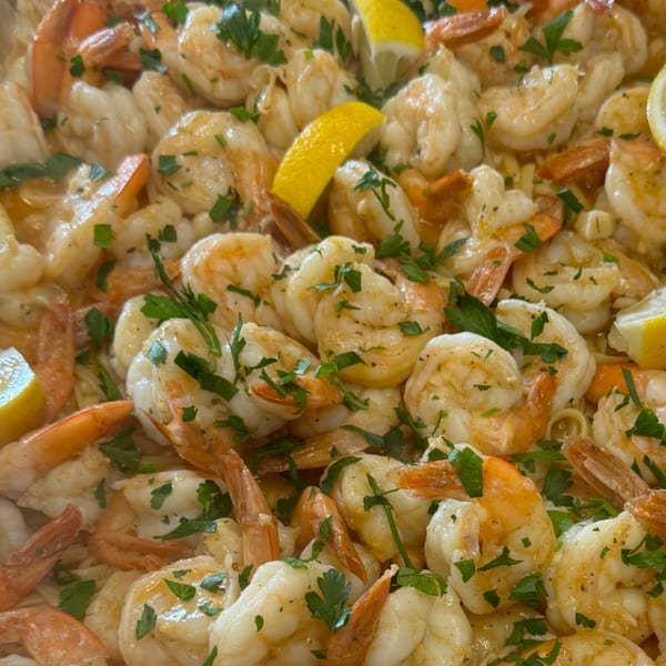 Close-up of shrimp scampi with lemon wedges and fresh parsley, a specialty at Angelo's Pizzeria and Ristorante.